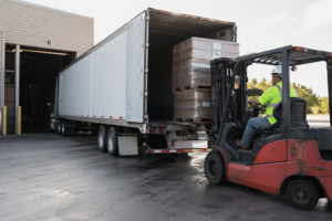 FTL shipping cost USA 2026 – forklift loading full truckload freight into trailer at warehouse dock