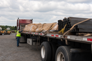 Flatbed trailer transporting lumber on highway in USA showing real-world flatbed shipping conditions and rising freight costs