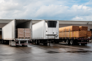 Comparison of dry van, reefer, and flatbed FTL trailers at a logistics warehouse loading area in the USA